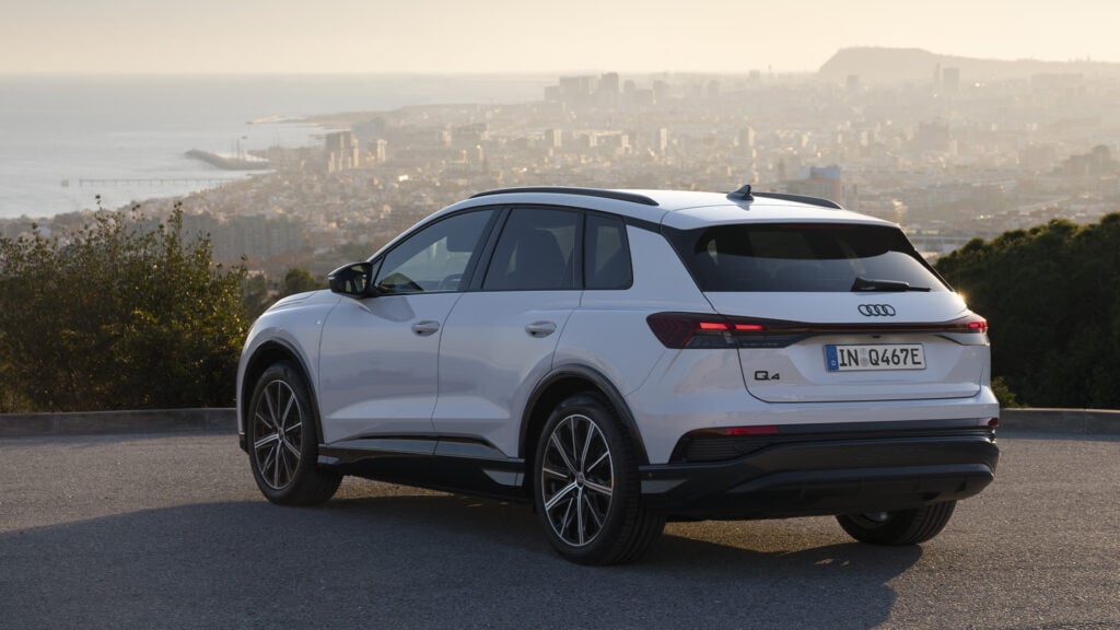 Audi Q4 40 e-tron i vitt fotad bakifrån med utsikt över en stad och kustlinje.