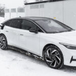 Vit Volkswagen ID. 7 laddar på Tesla Supercharger IV i snöigt vinterväder.
