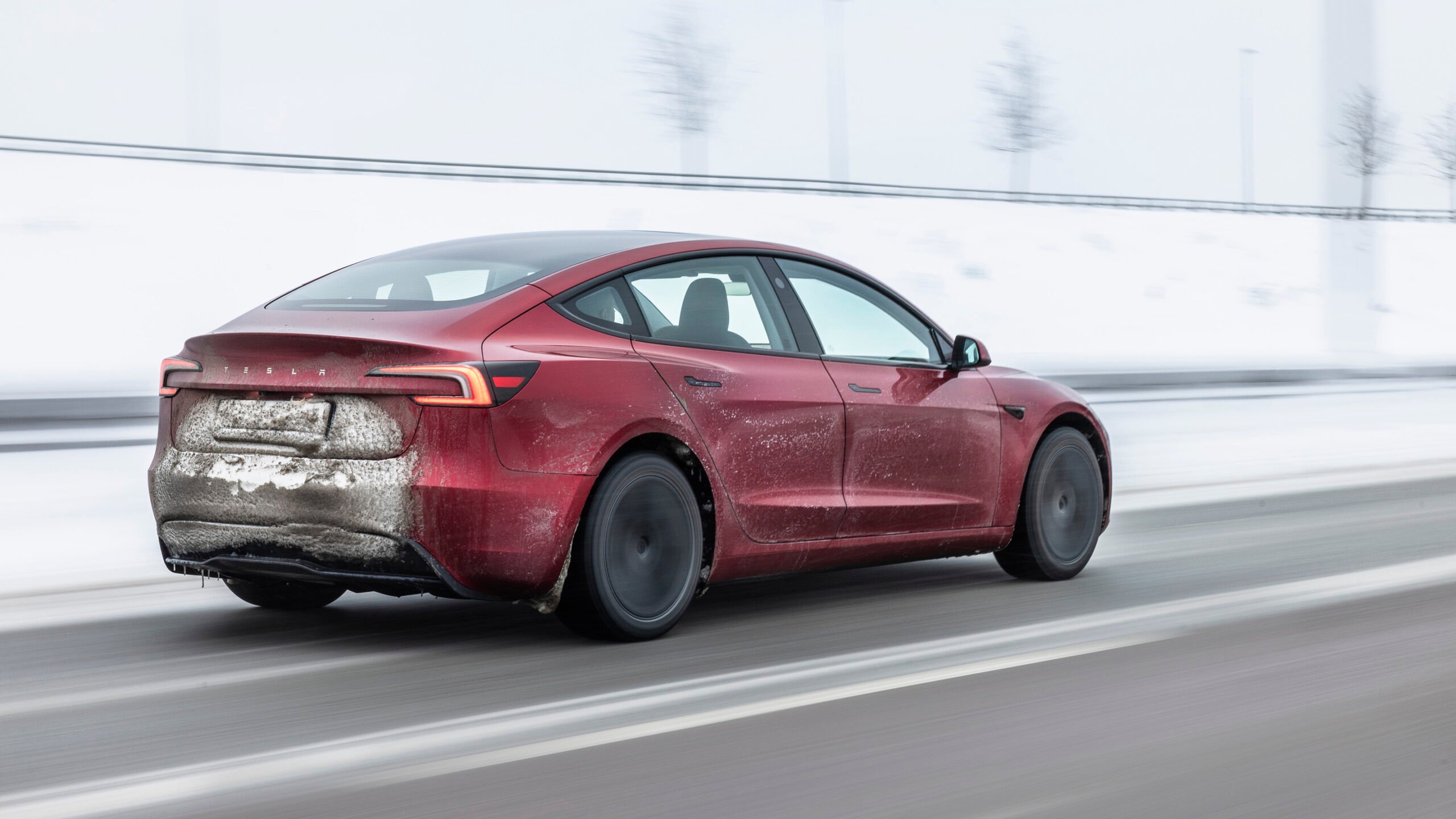 Tesla Model 3 facelift snett bakifrån på vinterväg.