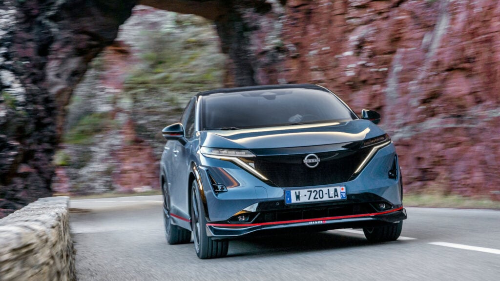 Nissan Ariya Nismo kör på en bergväg. Bild visar bilens front. 