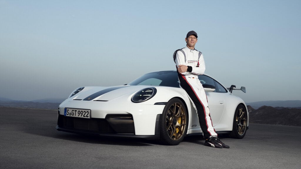 Jörg Bergmeister lutar mot en vit Porsche 911 GT3. 
