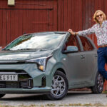 Journalist står bredvid en grön Kia Picanto.