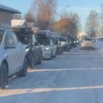 En vinterbild som visar en lång kö av Tesla-bilar parkerade längs en snötäckt gata i Malung, där bilister väntar på att få tillgång till laddstationen under en kall dag.