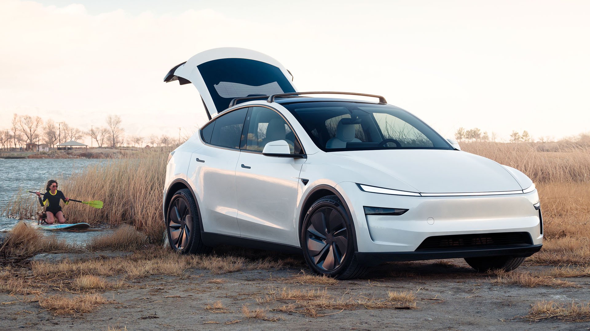 Nya Tesla Model Y i vitt står på strand med bakluckan öppen.
