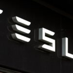 Tesla-logotyp på en svart bakgrund, fotograferad på en butik.