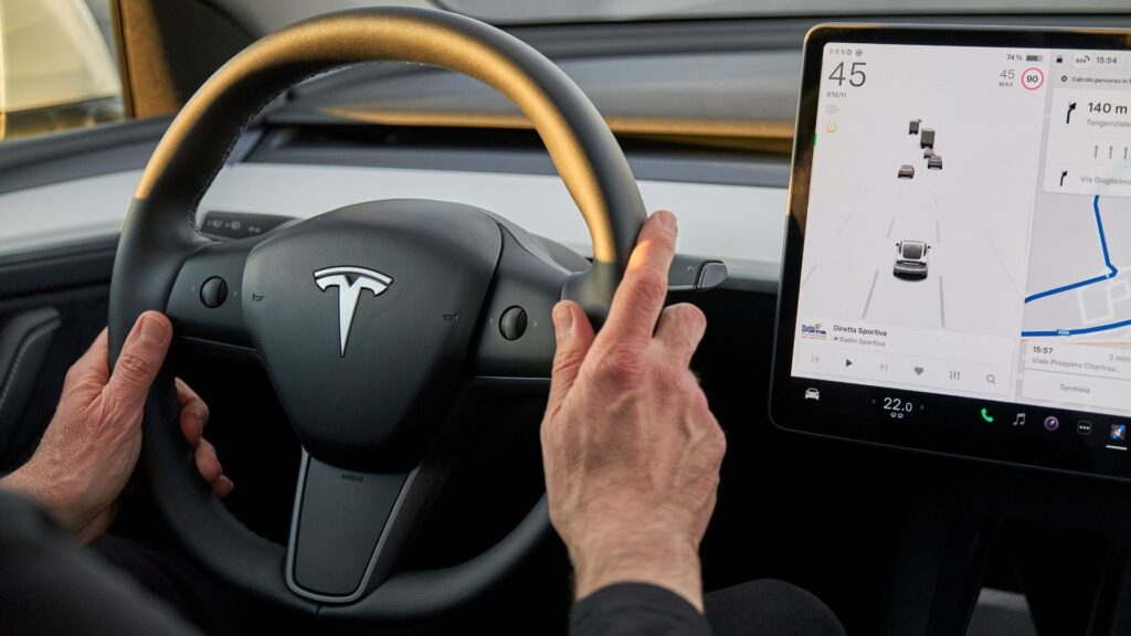 Förarens perspektiv i en Tesla Model Y, med fokus på ratten, pekskärmen och blinkersspakarna, som kan försvinna i framtida modeller.